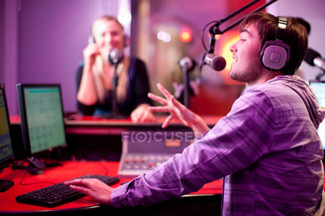 Jovem homem e mulher transmitindo em estúdio de gravação — Fotografia de Stock