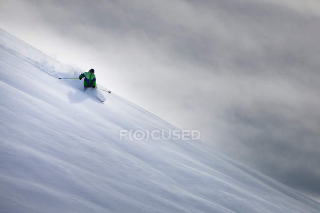 Людина катається на лижах на засніженому схилі пагорба — стокове фото