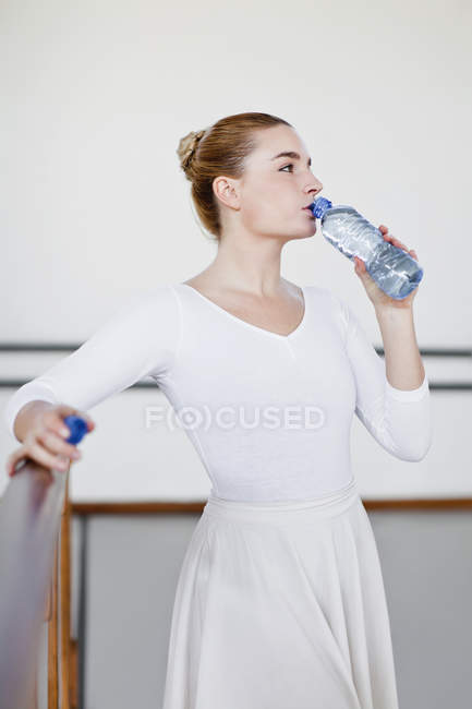 Ballet dancer drinking water in studio — Stock Photo