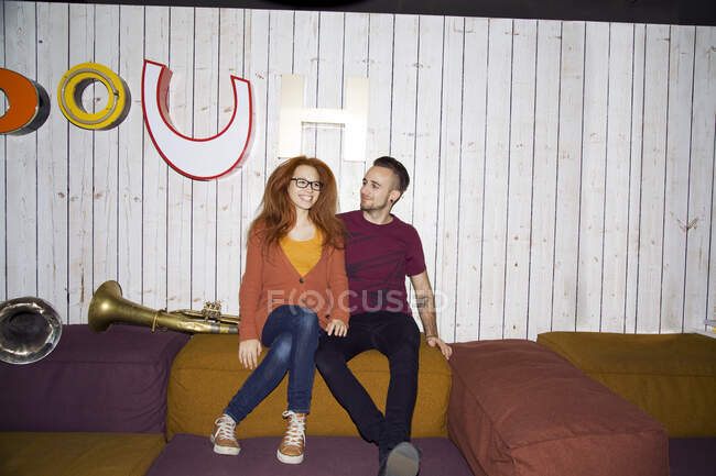 Retrato de pareja joven funky sentada en asientos en el club - foto de stock