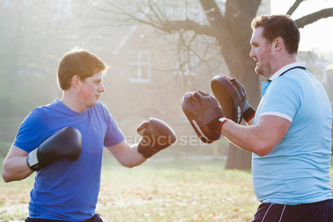 Boxer training with coach outdoors — Stock Photo