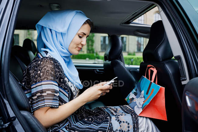 Mujer con pañuelo en la cabeza usando el teléfono celular - foto de stock