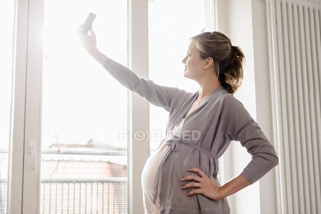 Mulher grávida tirando foto de si mesma — Fotografia de Stock