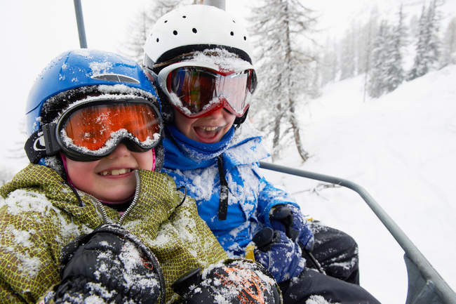 Snow covered children in ski lift, focus on foreground — Stock Photo