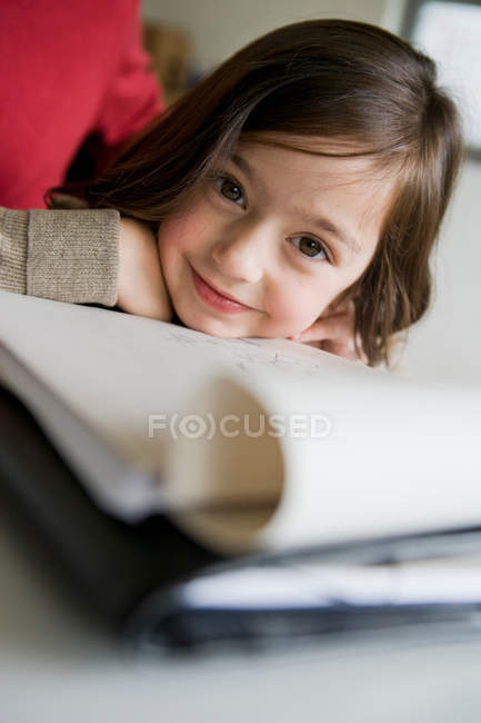 Sonriente chica haciendo la tarea en el escritorio - foto de stock