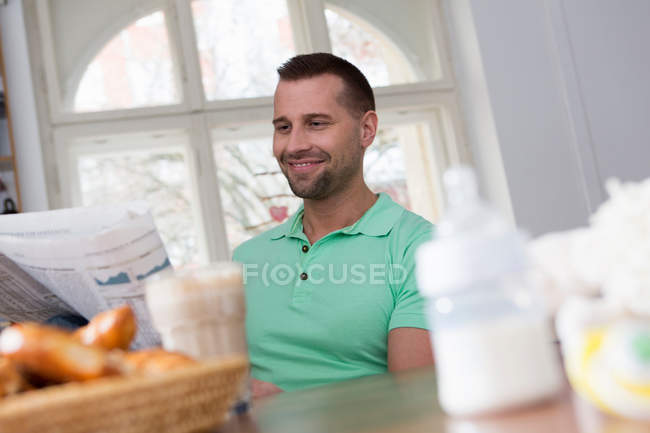 Mittlerer erwachsener Mann liest Zeitung am Frühstückstisch — Stockfoto