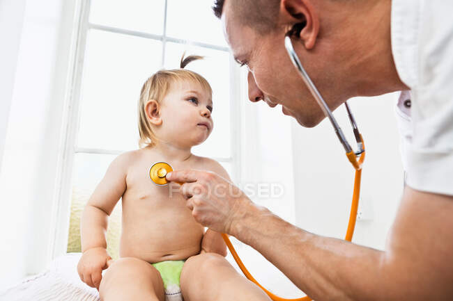 Doctor examining toddler girl with stethoscope — Stock Photo