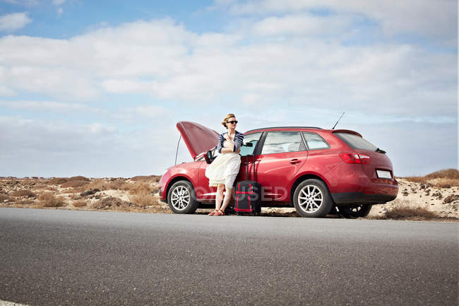 Mujer con coche averiado en la carretera rural - foto de stock