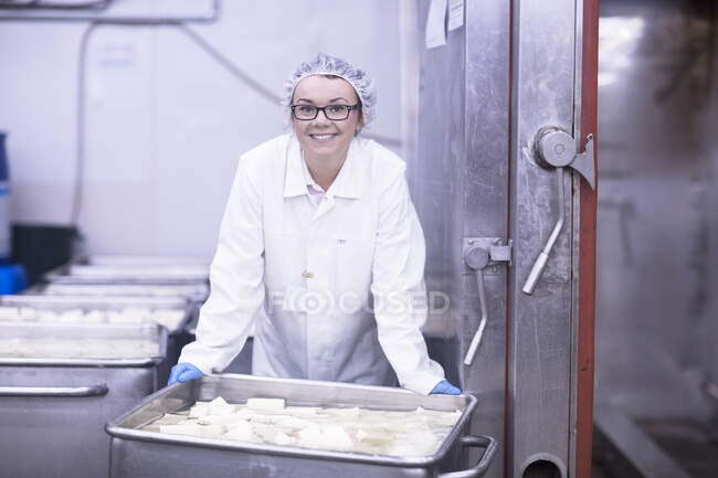 Trabajador de fábrica con bandeja de comida mirando a la cámara sonriendo - foto de stock