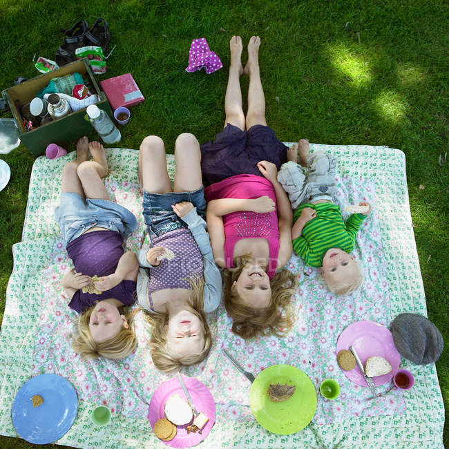 Vista elevada de los niños que ponen en la manta de picnic - foto de stock