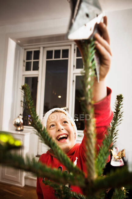 Niño sonriente decorando árbol de Navidad - foto de stock