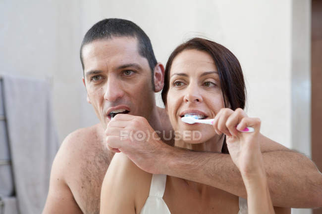 Pareja cepillándose los dientes en el baño - foto de stock