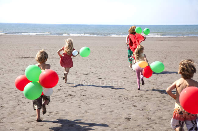 Mère avec quatre enfants sur la plage avec des ballons, Pays de Galles, Royaume-Uni — Photo de stock