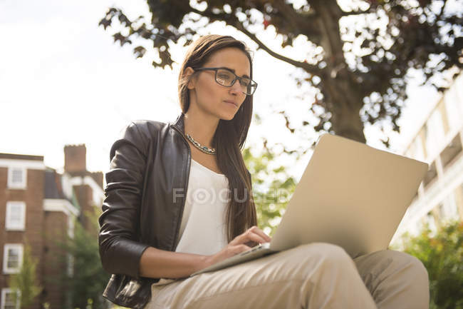 Businesswoman typing on laptop in city, London, UK — Stock Photo