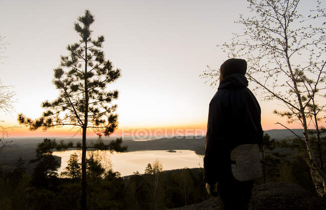 Турист, наслаждающийся видом на озеро на закате — стоковое фото