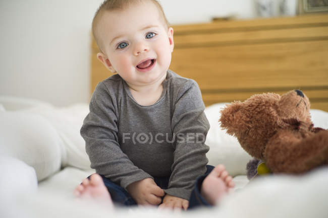 Bébé fille assis sur le lit regardant la caméra — Photo de stock