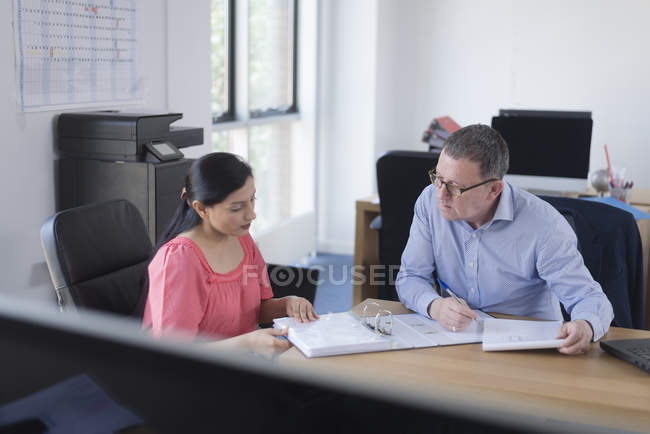 Businesswoman and businessman sitting at table in office and analyzing papers documents — Stock Photo