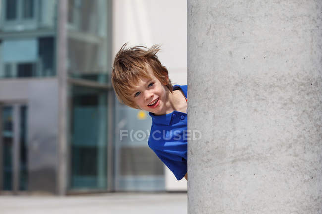 Мальчик выглядывает из-за колонны — стоковое фото