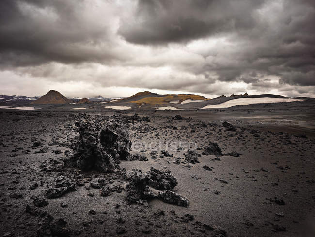 Rocas de lava en el campo con cielo nublado oscuro - foto de stock