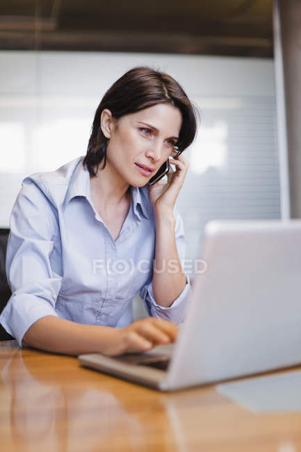Femme d'affaires sur téléphone portable et ordinateur portable — Photo de stock