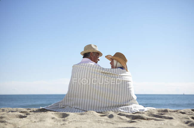 Couple portant des chapeaux de paille sur la plage — Photo de stock