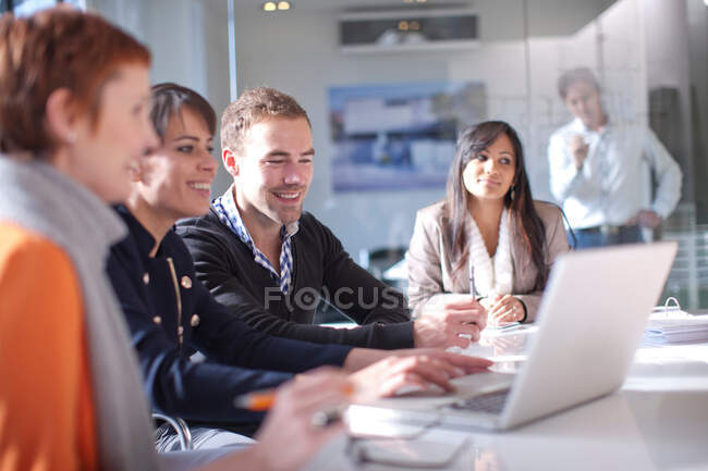 Geschäftsleute blicken lächelnd auf Laptop-Computer — Stockfoto