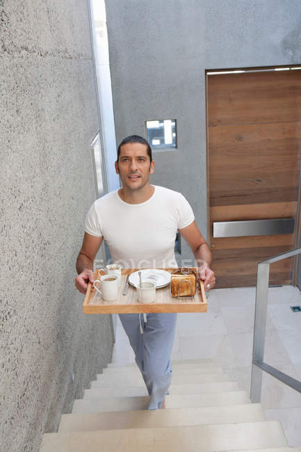 Mann trägt Tablett mit Lebensmitteln die Treppe hinauf — Stockfoto