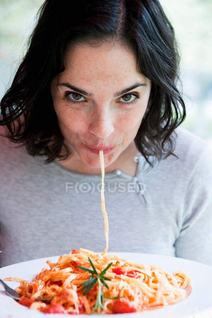 Donna che mangia Spaghetti e guarda la macchina fotografica — Foto stock