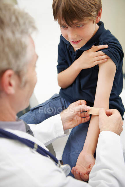 Доктор наносить штукатурку на молодого хлопчика — стокове фото