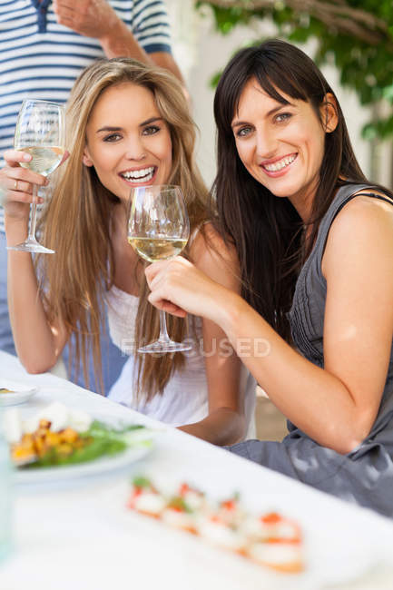 Amigos bebiendo vino en la mesa al aire libre - foto de stock