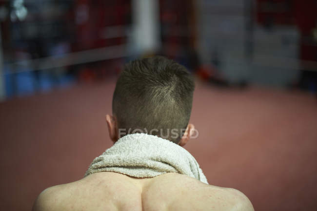Boxer sitting in corner of boxing ring, rear view — Stock Photo