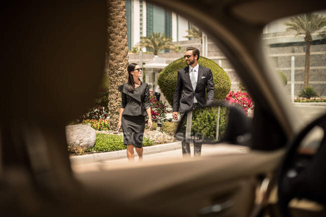 Vista de la ventana del coche de la mujer de negocios y hombre caminando fuera del hotel, Dubai, Emiratos Árabes Unidos - foto de stock