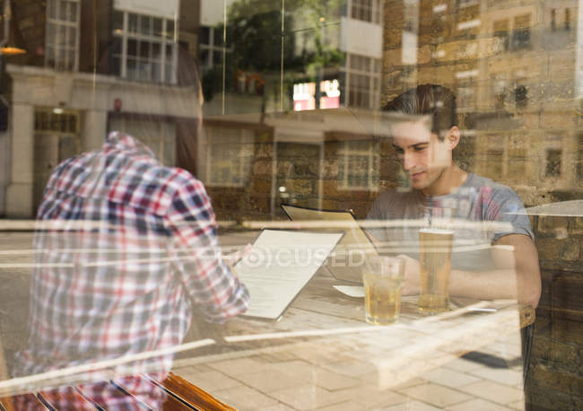 Vista finestra di giovani coppie menu di lettura nel ristorante — Foto stock