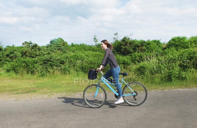 Jeune femme vélo sur la voie de campagne — Photo de stock