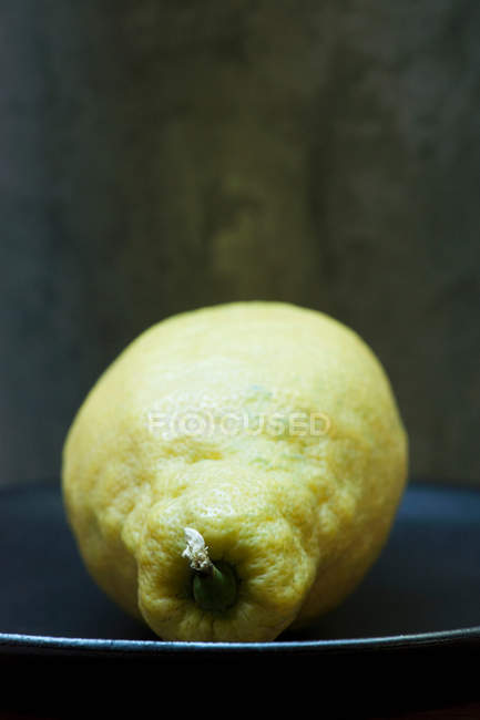 Close up shot of unwaxed lemon on plate — Stock Photo