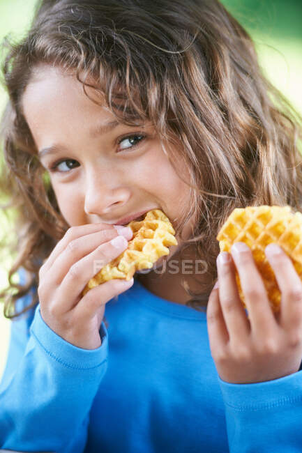 Chica sonriente comiendo gofres - foto de stock