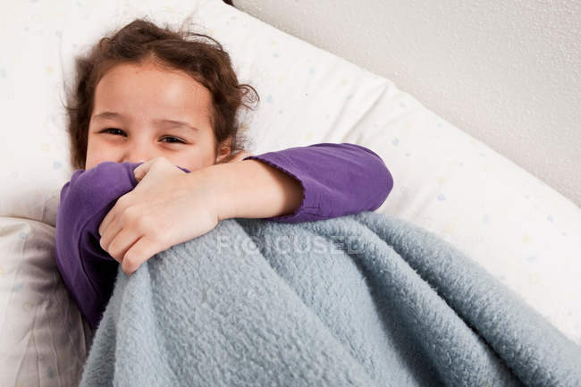 Little girl hiding behind blanket — Stock Photo