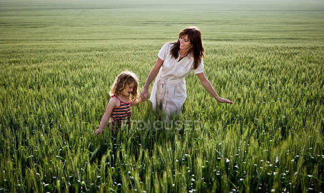 Женщина и ребенок ходят по пшеничному полю — стоковое фото