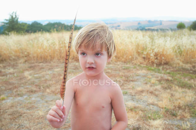 Niño jugando con plumas en el campo - foto de stock