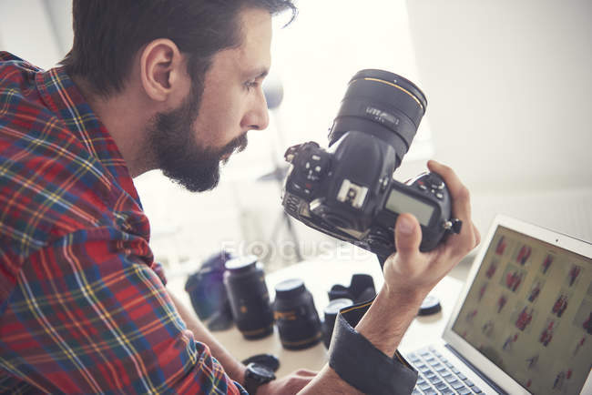 Homme photographe examen séance photo sur ordinateur portable en studio — Photo de stock