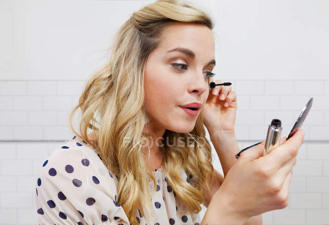 Frau trägt Wimperntusche im Spiegel auf — Stockfoto