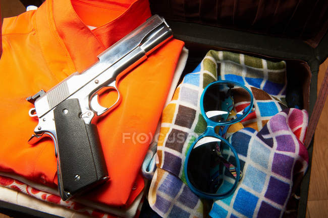 Gun and sunglasses in suitcase — Stock Photo