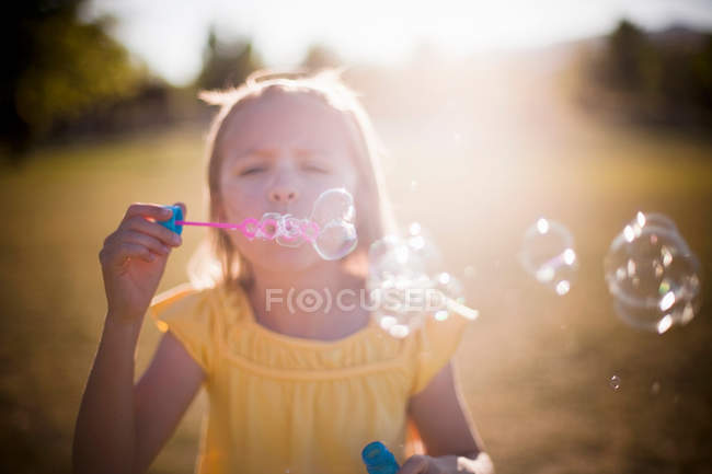 Chica joven soplando burbujas - foto de stock