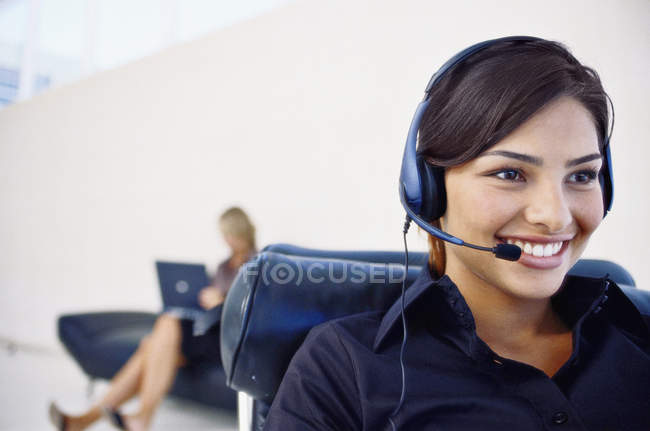 Lächelnde Geschäftsfrau mit Headset, Frau im Hintergrund — Stockfoto
