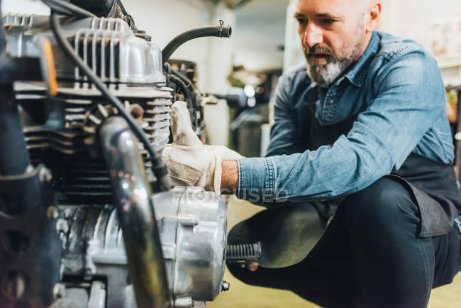 Reifer Mann arbeitet in Garage an Motorrad — Stockfoto