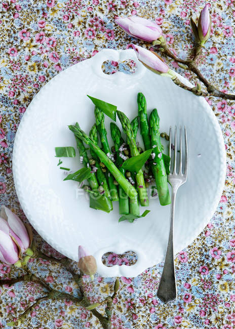 Vista dall'alto di piatto di asparagi con fiori sul tavolo — Foto stock