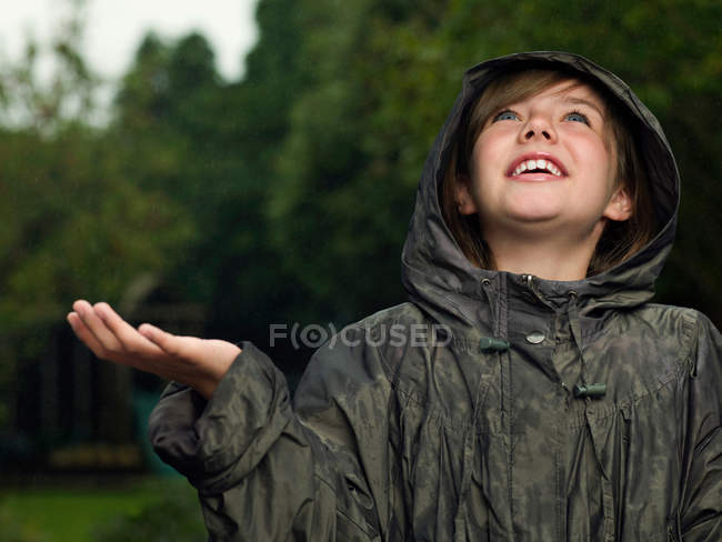 Girl holding hand out to catch rain — Stock Photo