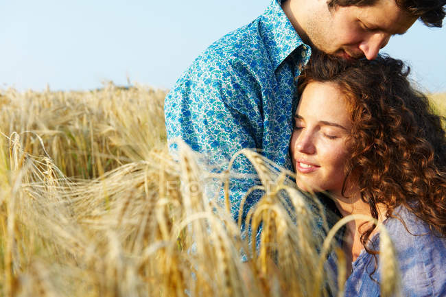 Couple assis dans un champ de blé, souriant — Photo de stock