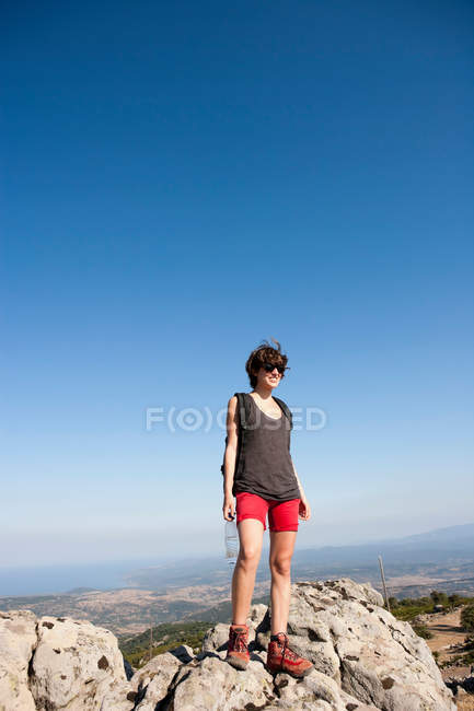 Escursionista in piedi su rocce sulla collina — Foto stock