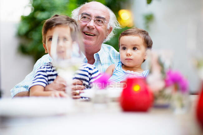 Дедушка и дети обедают — стоковое фото
